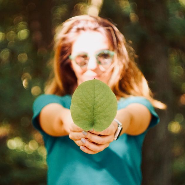 Frau im Wald mit Blatt in der Hand